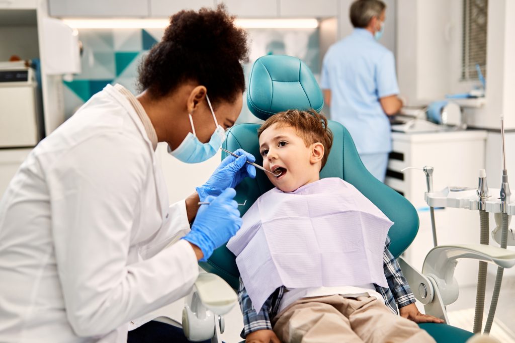 Little boy getting his teeth checked by dentist at dental clinic.